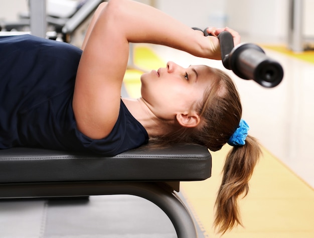 Joven deportista en ropa deportiva en entrenamiento de equipos de fitness con pesas en el gimnasio