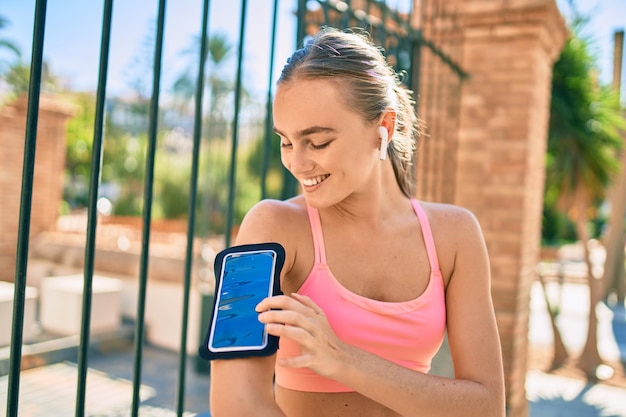 Joven deportista rubia usando auriculares haciendo ejercicio en la ciudad