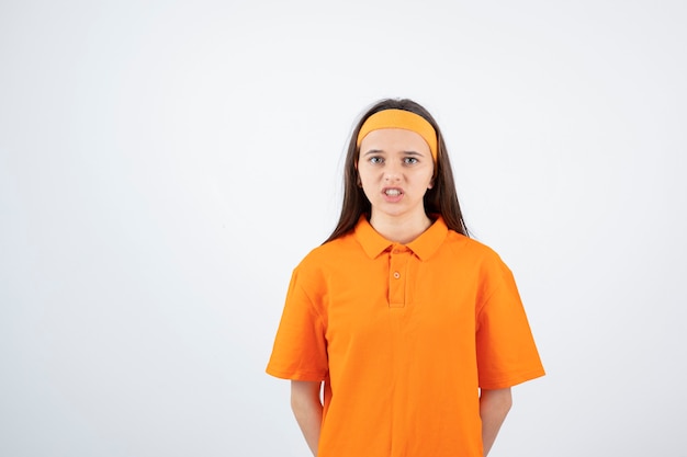 joven deportista en traje naranja de pie sobre blanco.