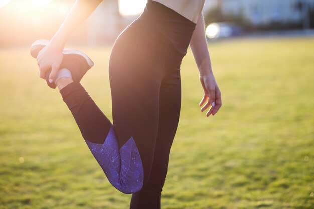 joven deportiva haciendo ejercicio antes de correr en el campo de la mañana al aire libre