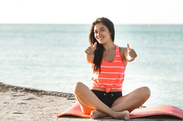 Joven deportiva haciendo ejercicios de yoga en la playa