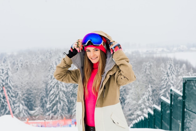 Joven deportiva en invierno con snowboard, gafas