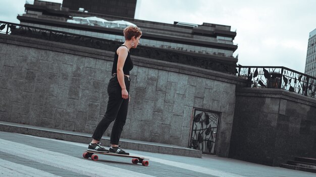 Joven deportiva montando en el longboard en el parque