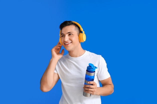 Joven deportivo con auriculares y agua en color