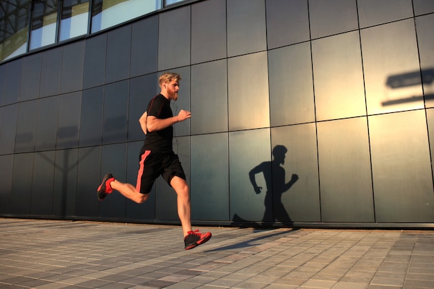 Joven deportivo corriendo al aire libre para mantenerse saludable, al atardecer o al amanecer. Corredor