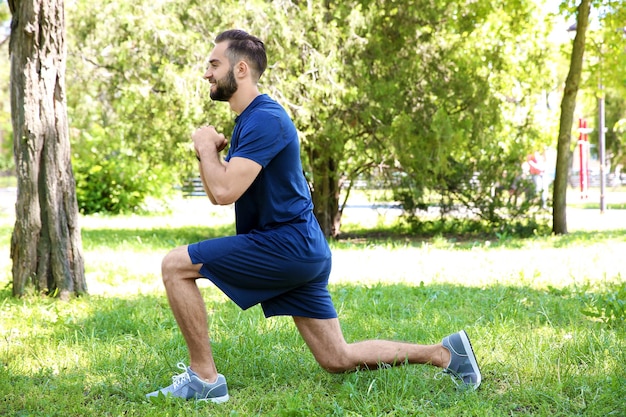 Joven deportivo haciendo ejercicios deportivos para piernas en el parque