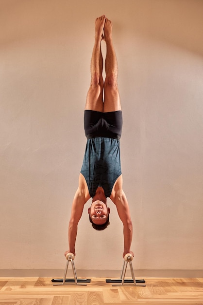 Joven deportivo trabajando en yoga pilates entrenamiento físico haciendo el pino Adho Mukha Vrksasana mirando hacia abajo Tree Pose vista posterior low key shot