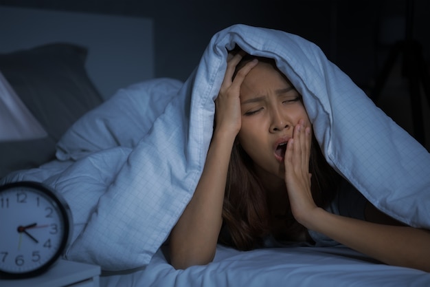 Una joven deprimida acostada en la cama no puede dormir por insomnio.