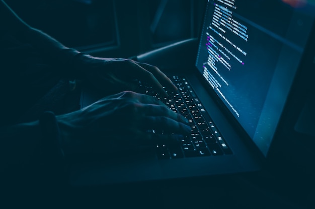 Un joven desarrollador está programando un guión de código tarde en la noche con hermosas luces de la ciudad