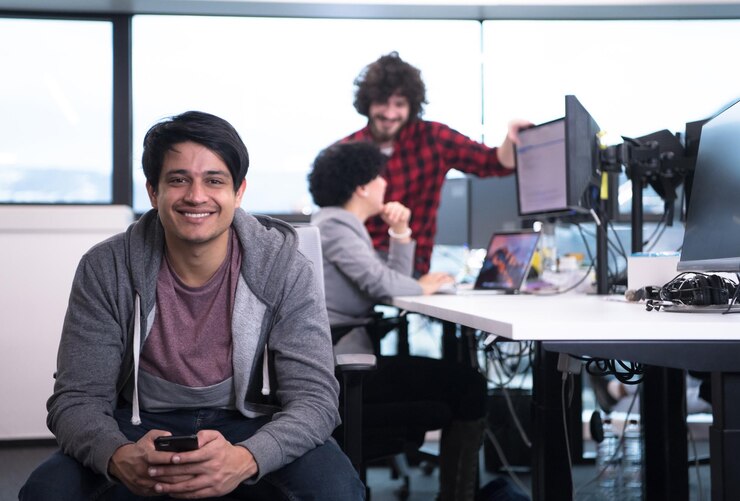 Foto joven desarrollador de software masculino indio que usa mensajes de escritura de teléfonos móviles mientras se toma un descanso en la oficina de inicio creativa moderna