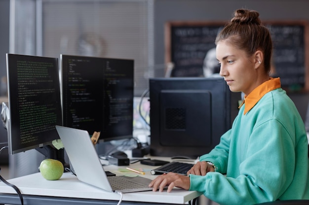 Joven desarrolladora desarrollando programas en computadora durante su trabajo en la oficina de TI