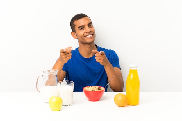 Joven desayunando en una mesa señalando