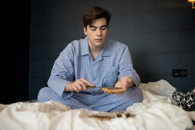 Joven desayunando sentado en la cama