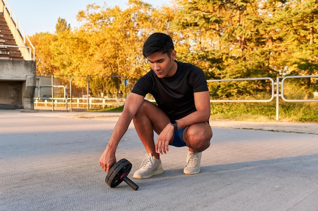 Joven descansando después de entrenar abdominales con un rodillo abdominal