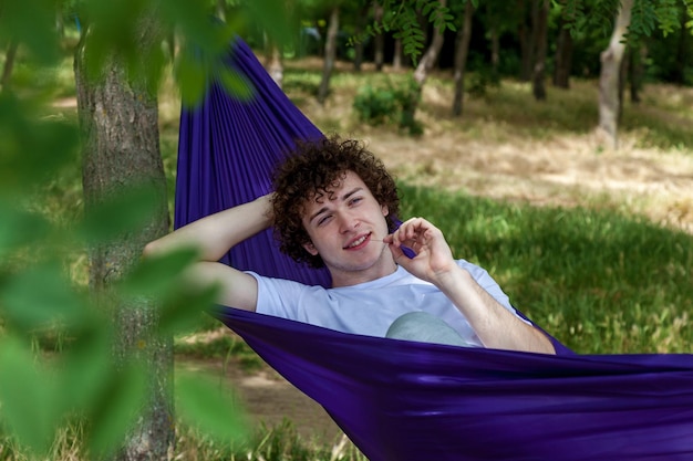 Foto un joven está descansando en una hamaca púrpura en la naturaleza disfrutando de la soledad y el silencio