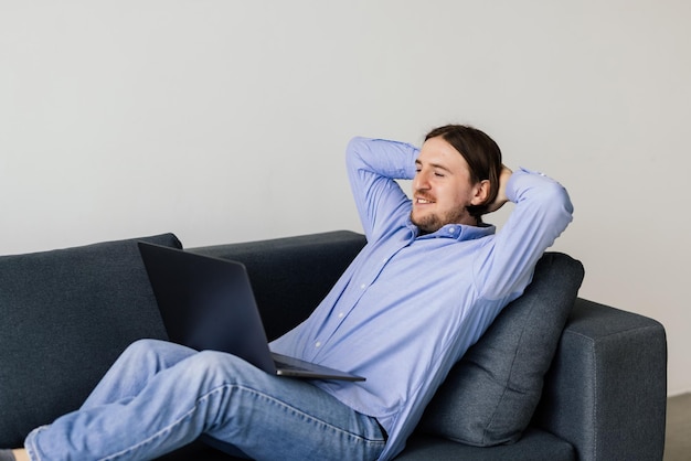 Joven descansando en un sofá con una computadora portátil