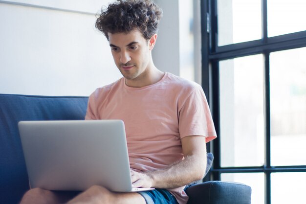 Joven descansando en el sofá con una computadora portátil