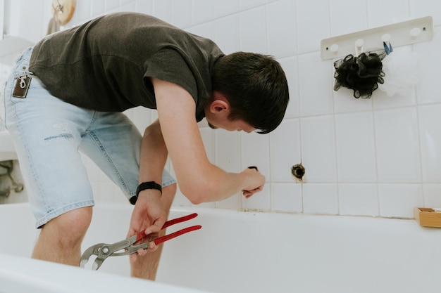 Foto un joven desenrolla el tubo del grifo del baño.