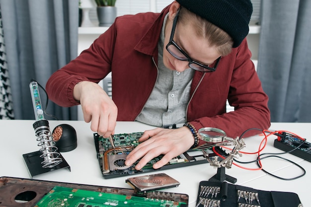 Joven desmontando la placa base del ordenador.