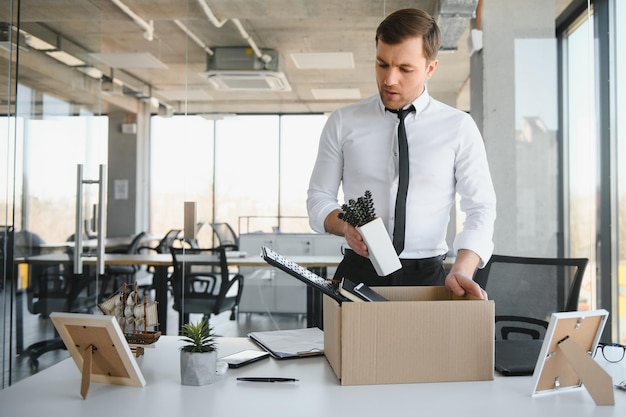 Foto joven despedido empacando sus cosas en la oficina