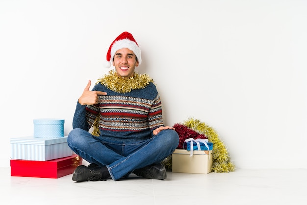 Joven en el día de Navidad tiene espacio de copia en una palma, mantener la mano sobre la mejilla Sorprendido y encantado.