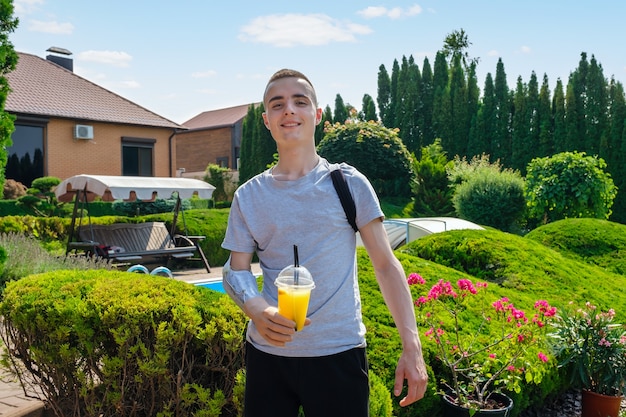 Joven con discapacidad sosteniendo cóctel en prótesis mientras está de pie al aire libre