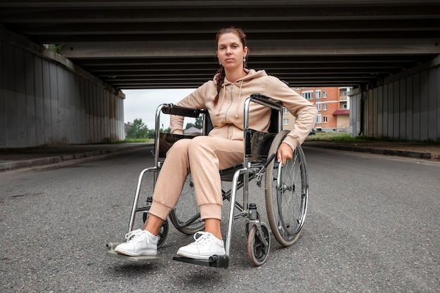 Una joven discapacitada sentada en una silla de ruedas en la calle. El concepto de silla de ruedas, persona discapacitada, vida plena, paralizada, persona discapacitada, atención médica.