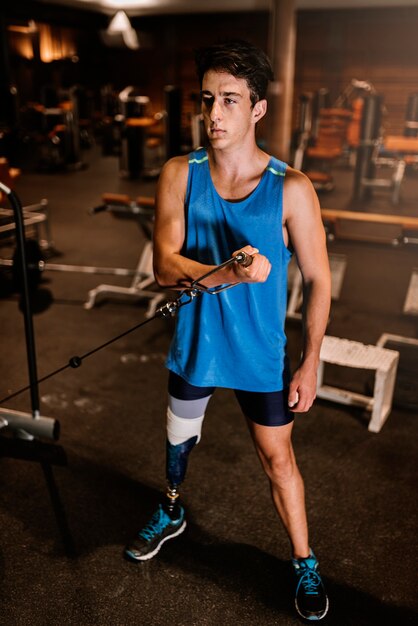 Joven discapacitado entrenando en el gimnasio. Concepto de deportista discapacitado.