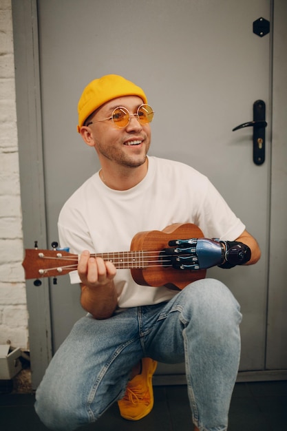 Joven discapacitado con prótesis de mano artificial toca la guitarra en la tienda