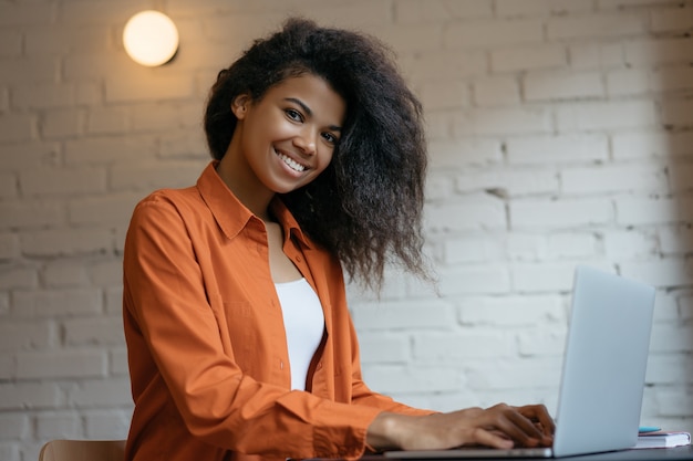 Joven diseñador africano usando laptop, trabajando desde casa