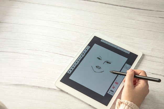 Joven diseñador creativo sosteniendo lápiz óptico dibujo en la pantalla de la tableta digital en un escritorio de madera con