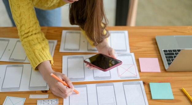 joven diseñador está dibujando una pantalla de teléfono inteligente y una aplicación.