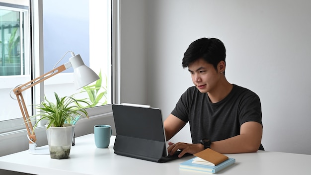 Un joven diseñador está trabajando en una tableta de computadora en el espacio de trabajo.