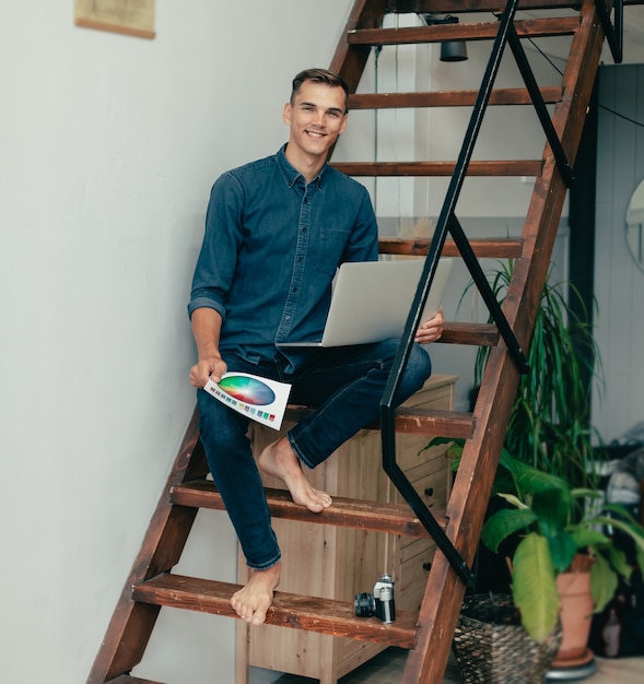 Joven diseñador sentado en los escalones de su casa Studio vida doméstica