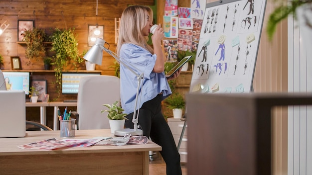 Joven diseñador tomando café y mirando la pizarra y siguiendo la evolución del proyecto. espacio de trabajo creativo