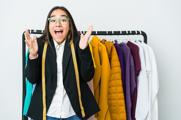 Joven diseñadora asiática aislada en blanco celebrando una victoria o un éxito, se sorprende y se sorprende.