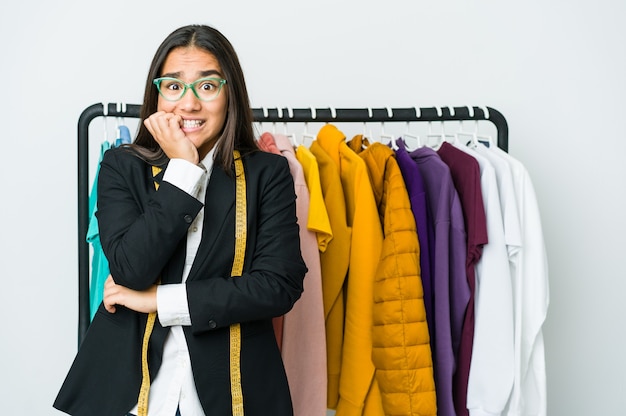 Joven diseñadora asiática aislada en la pared blanca mordiéndose las uñas, nerviosa y muy ansiosa