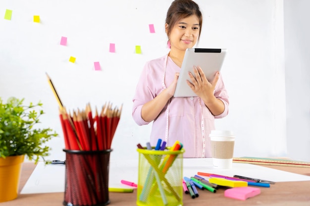 Joven diseñadora gráfica hipster que usa tableta gráfica digital mientras trabaja en un espacio de trabajo moderno con una mesa de madera tableta de diseño genérico