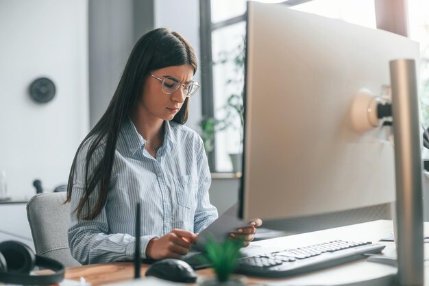 Foto la joven diseñadora está en la oficina moderna trabajando por computadora