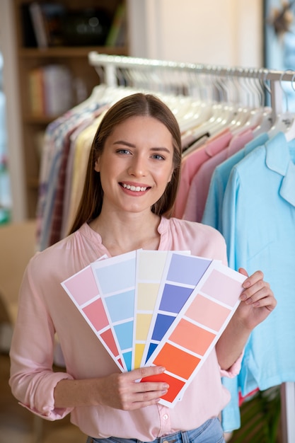 Joven diseñadora sonriente con escalas de color en sus manos