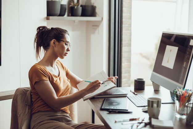 Una joven diseñadora trabaja en una computadora desde su oficina en casa.