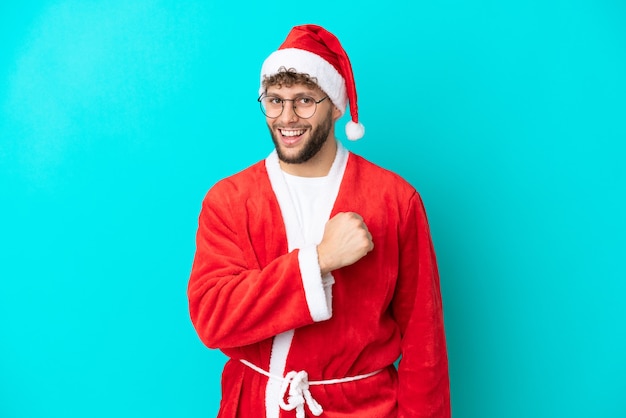 Joven disfrazado de Santa Claus aislado sobre fondo azul celebrando una victoria