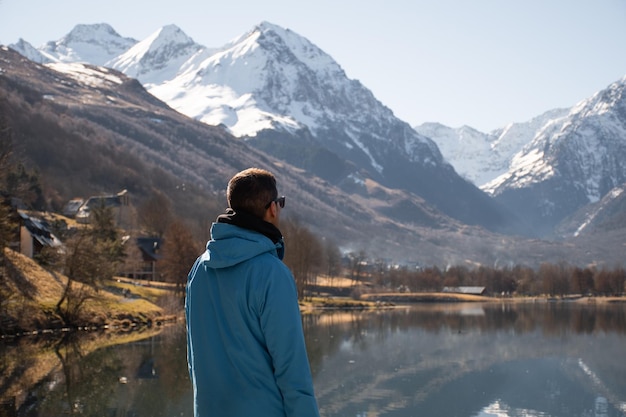 Joven disfrutando de una hermosa vista de un lago y montañas nevadas en Loudenvielle Francia