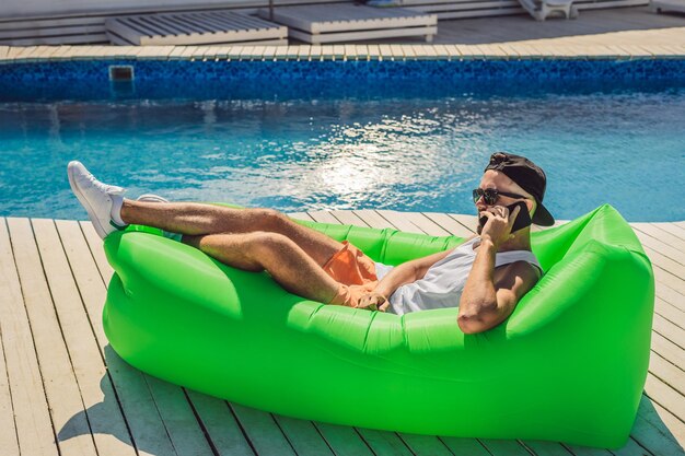 Foto joven disfrutando del ocio tumbado en el sofá de aire lamzac cerca de la piscina