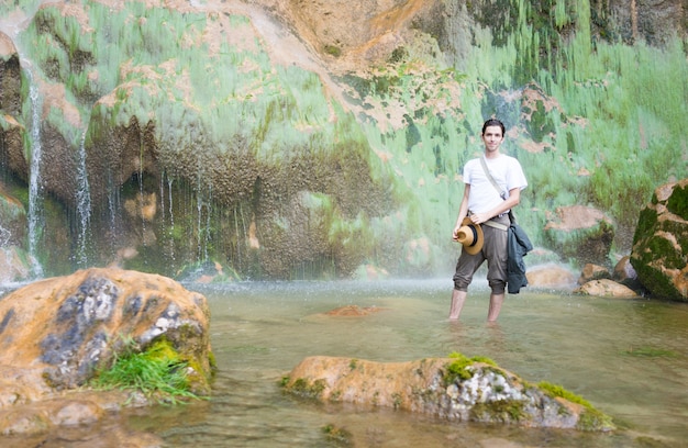 Joven disfrutando en el parque natural en la base de la gran cascada