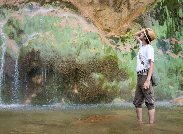 Joven disfrutando en el parque natural en la base de la gran cascada