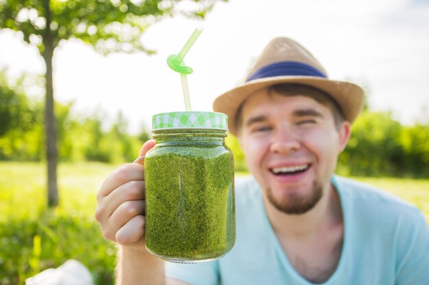 Joven divertido tiene batido de desintoxicación con pajita. Concepto de estilo de vida saludable, personas y alimentos.