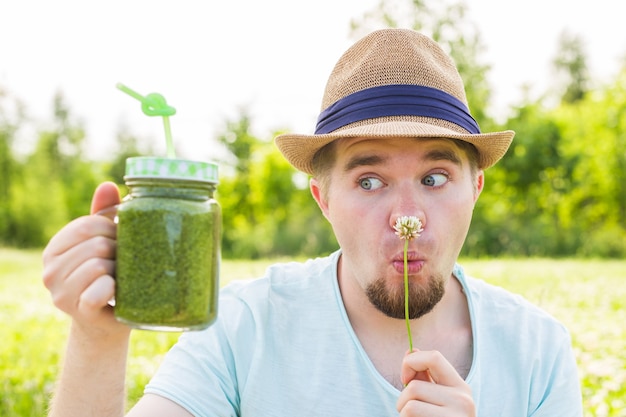 Foto joven divertido tiene batido de desintoxicación con pajita. concepto de estilo de vida saludable, personas y alimentos.