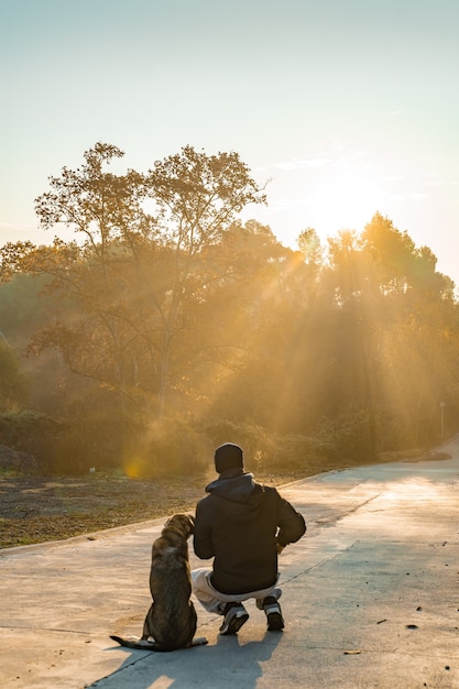 Joven divirtiéndose con su perro en la naturaleza con los rayos del sol de la mañana amo a mi perro