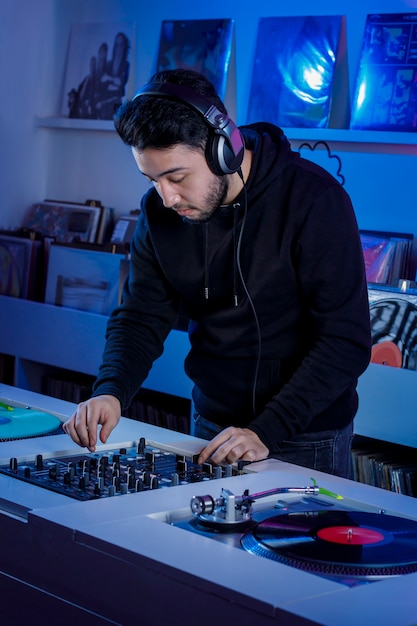 Joven dj colocando un disco de vinilo en un tornamesa para mezclar musica en una tienda de discos